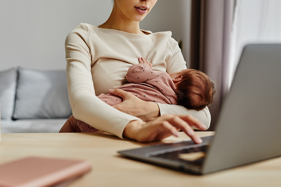 Mother breastfeeding while working laptop