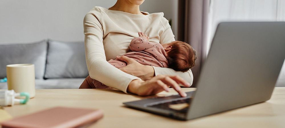 Mother breastfeeding while working laptop