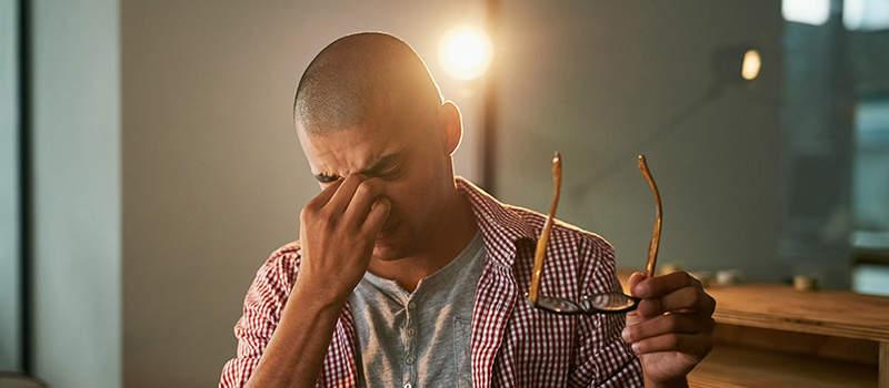 Man with headache holding glasses