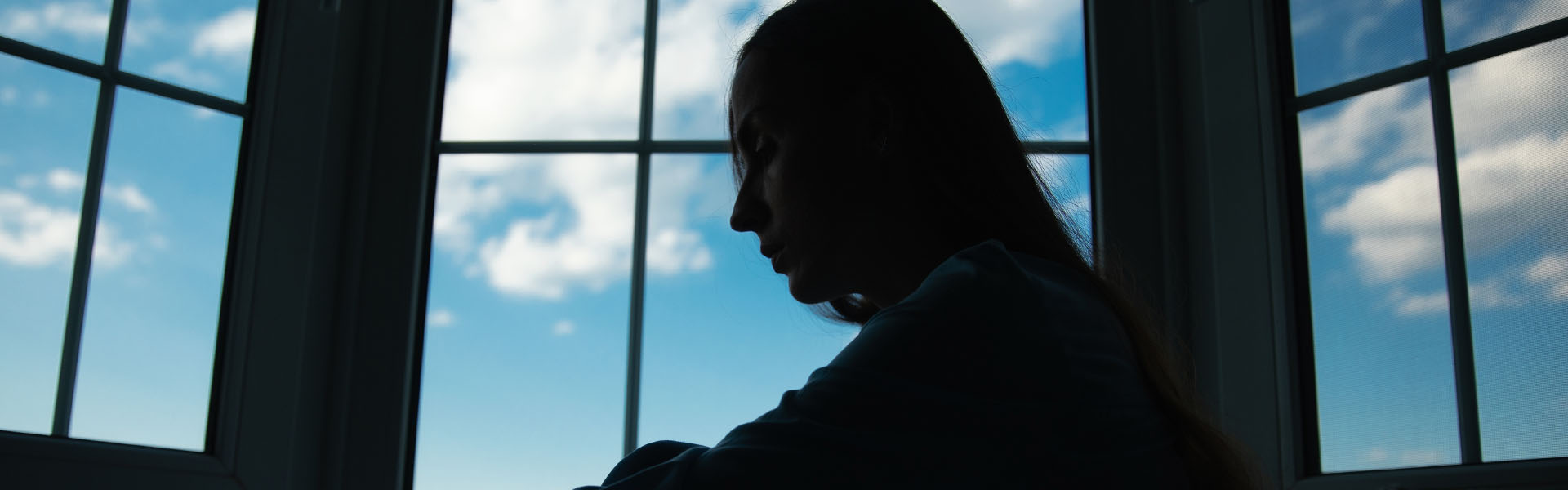 Silhouette person sitting by window