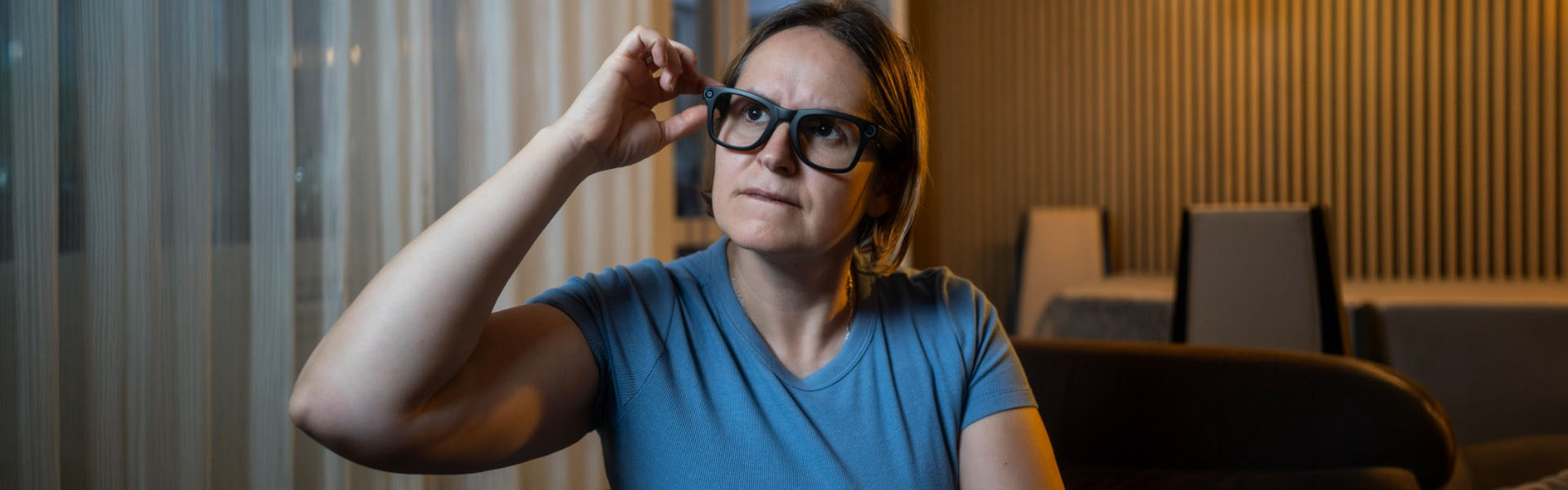 Woman adjusting glasses indoors evening