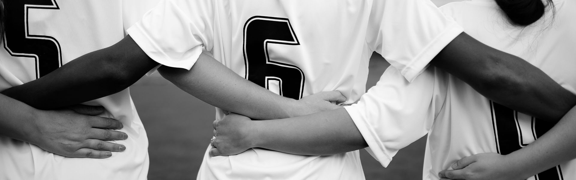women in football teammates linking arms together