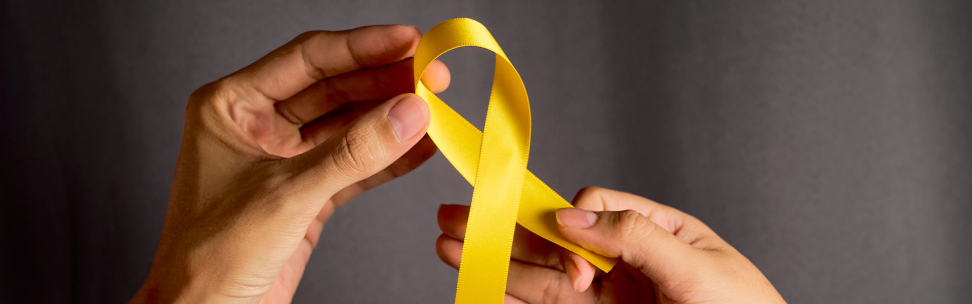 Hands holding yellow awareness ribbon