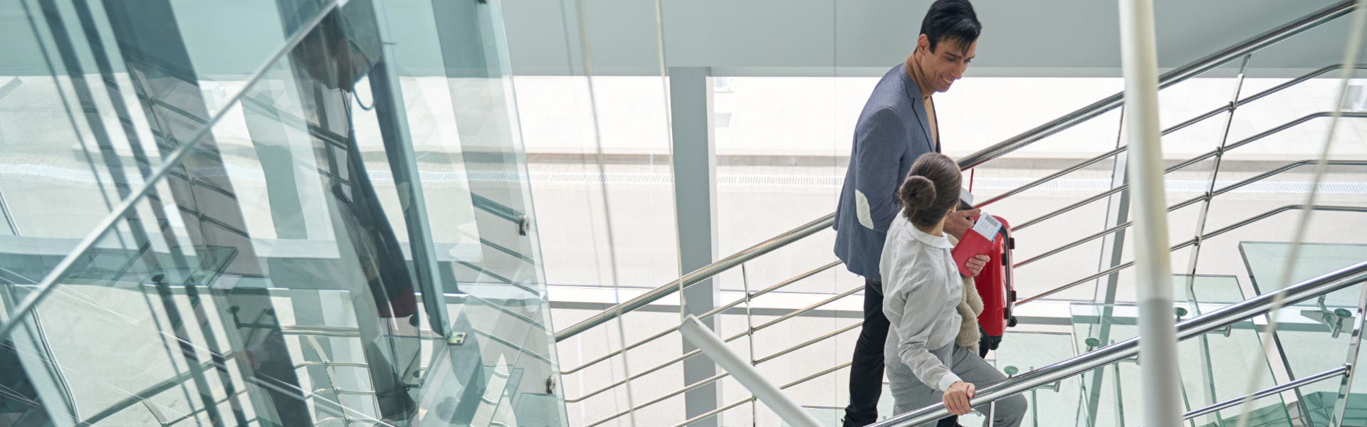 Workers walking up a staircase in the glass-clad atrium of a building