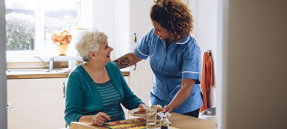 Caregiver assisting elderly woman kitchen