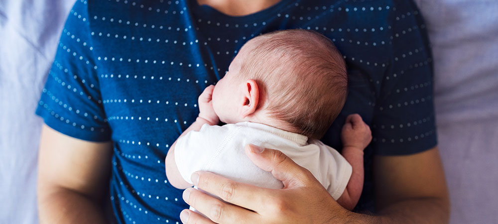 Father holding newborn baby close