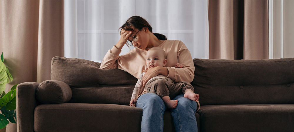 Stressed mother holding baby sofa