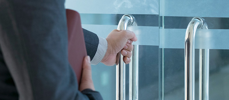 Businessperson opening glass door