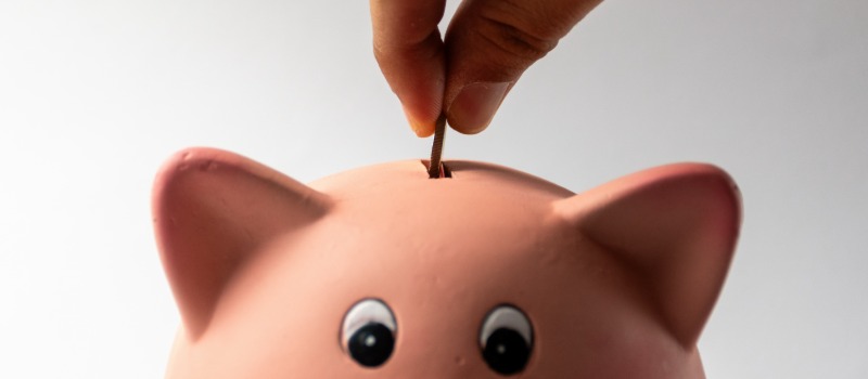 Hand inserting coin piggy bank
