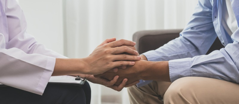 Doctor comforting patient holding hands