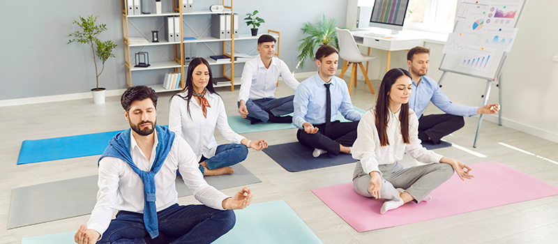 Office workers meditating on mats