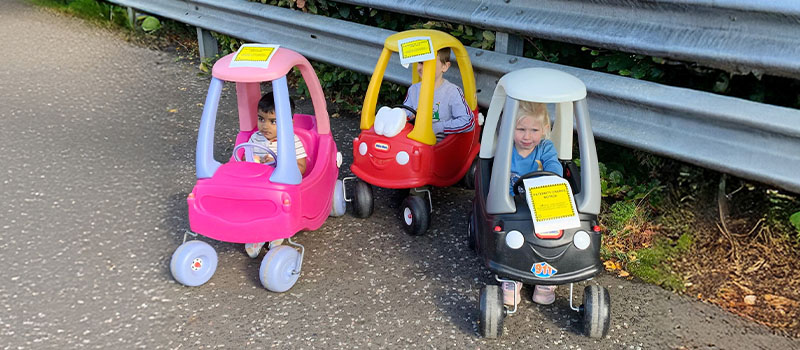 Hundreds of dads plaster 'paternity charge' notices over the UK to protest underpaid paternity leave Kids in toy cars parked
