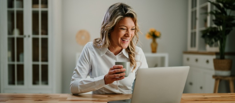Smiling woman video calling laptop from home