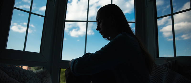 Silhouette person sitting by window