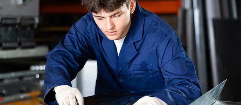 Factory worker handling metal sheet