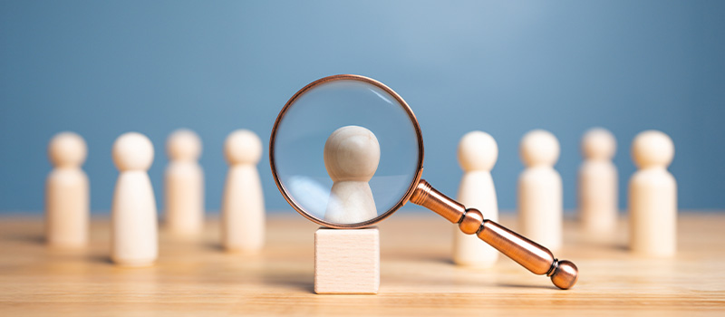 Magnifying glass focusing wooden figure