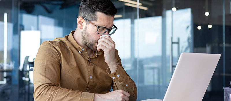 7 in 10 UK workers admit to pretending to be well at work Stressed man working on laptop