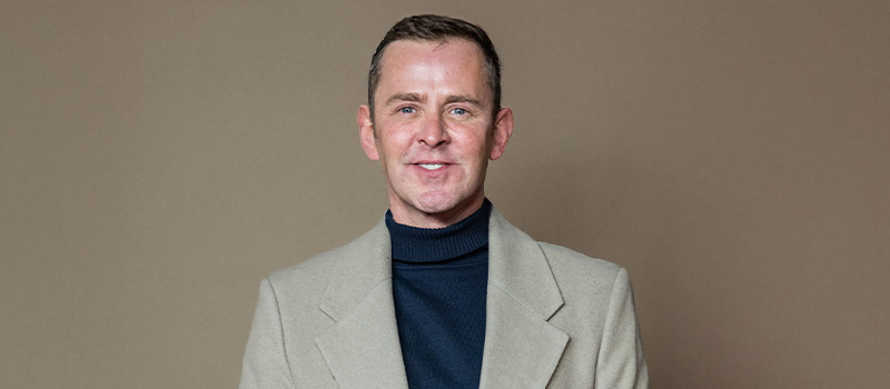 Man in beige blazer smiling