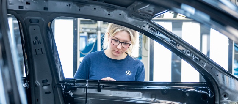Woman inspecting car frame assembly