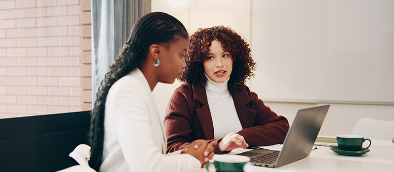 Businesswomen discussing project at laptop