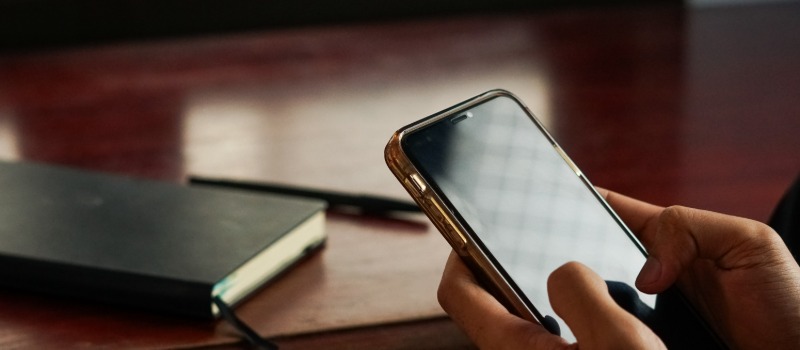 Person using smartphone near notebook