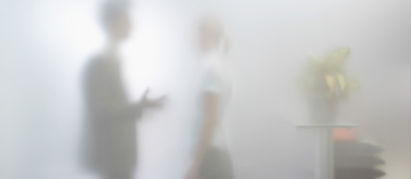 How whistleblowing still goes wrong inside good HR teams Two people standing behind opaque glass conversing in an office setting