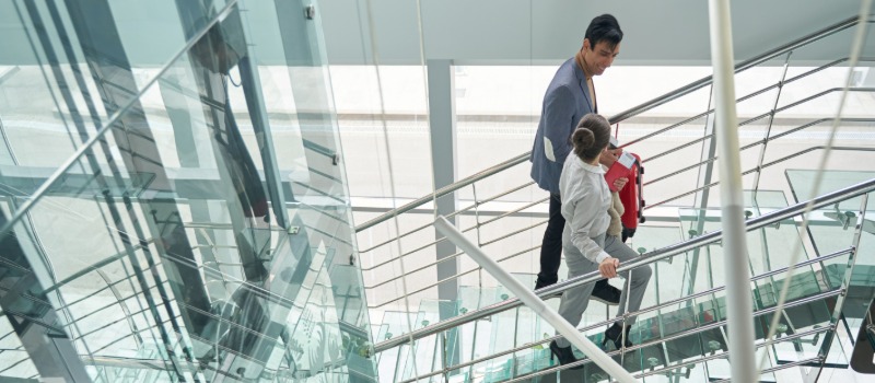 Workers walking up a staircase in the glass-clad atrium of a building