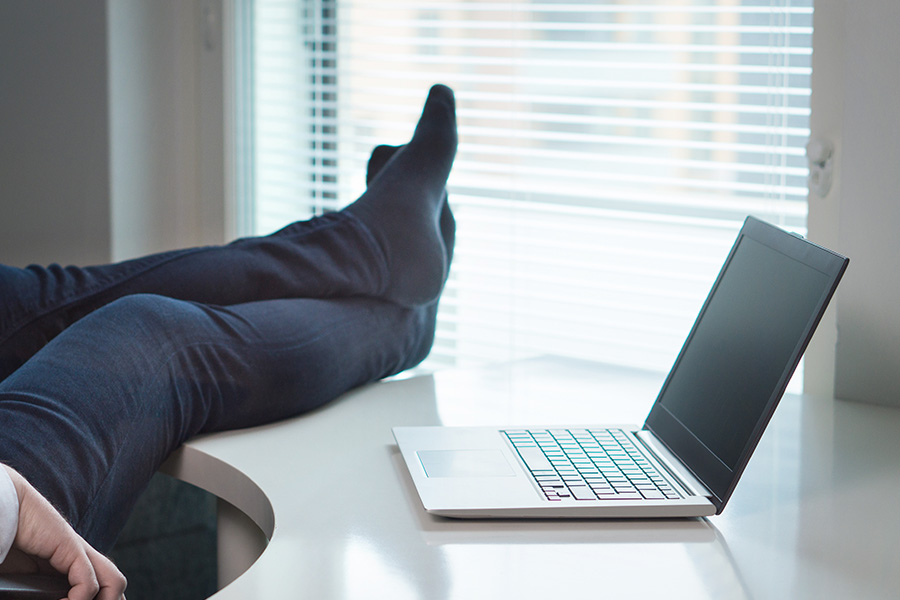 American workers cause a stink with barefoot office trend Relaxing at desk with laptop