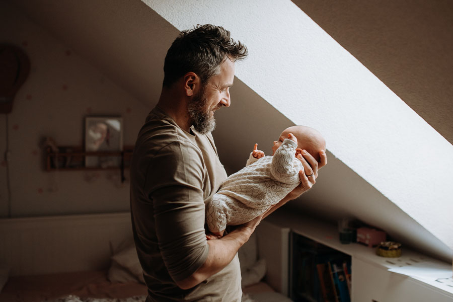 Father holding newborn by window