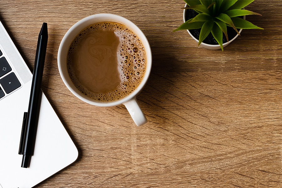 Coffee, laptop, pen, plant, desk