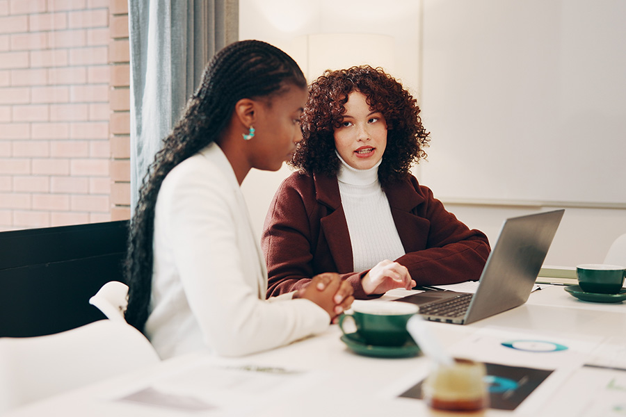 Why women are leading on engagement but may still suffer burnout Businesswomen discussing project at laptop