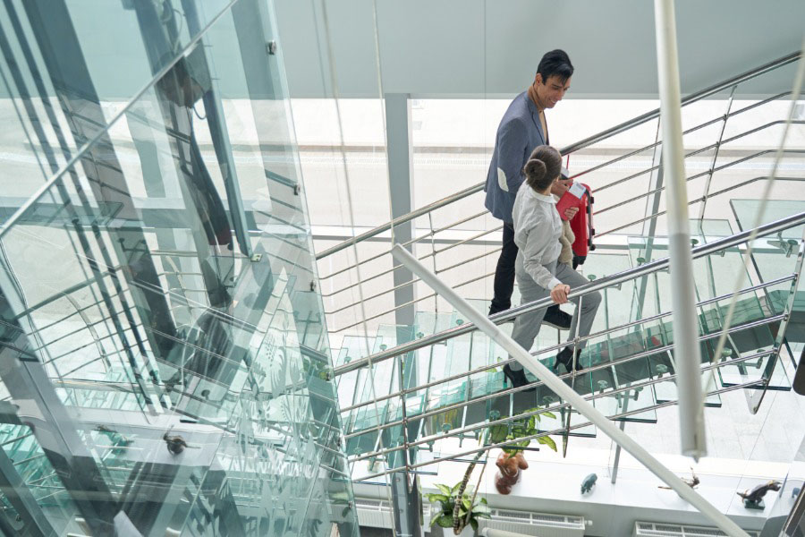 Workers walking up a staircase in the glass-clad atrium of a building